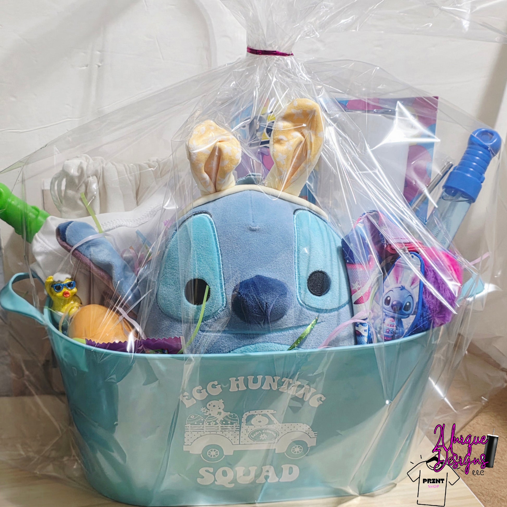 Gift basket with plush toy, toys, and a blue bucket labeled 'Egg Hunting Squad' on a white background.